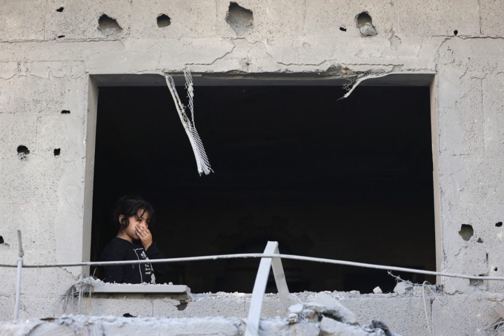 A Palestinian girl looks out a window of a damaged building at the Nuseirat refugee camp in the central Gaza Strip on November 17, 2023, amid ongoing battles between Israel and the militant group Hamas. (Photo by MAHMUD HAMS / AFP)