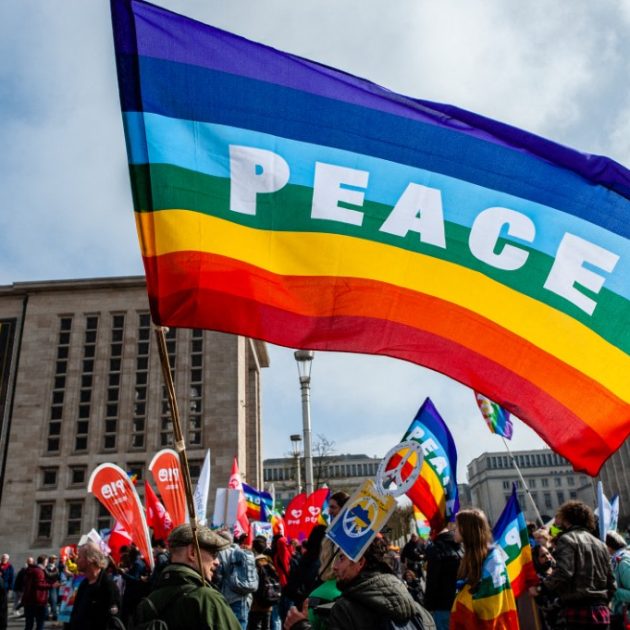 A man is holding a rainbow flag with the word Peace on it, during the National peace rally organized in Brussels, on March 27th, 2022. (Photo by Romy Arroyo Fernandez/NurPhoto) (Photo by Romy Arroyo Fernandez / NurPhoto / NurPhoto via AFP)
