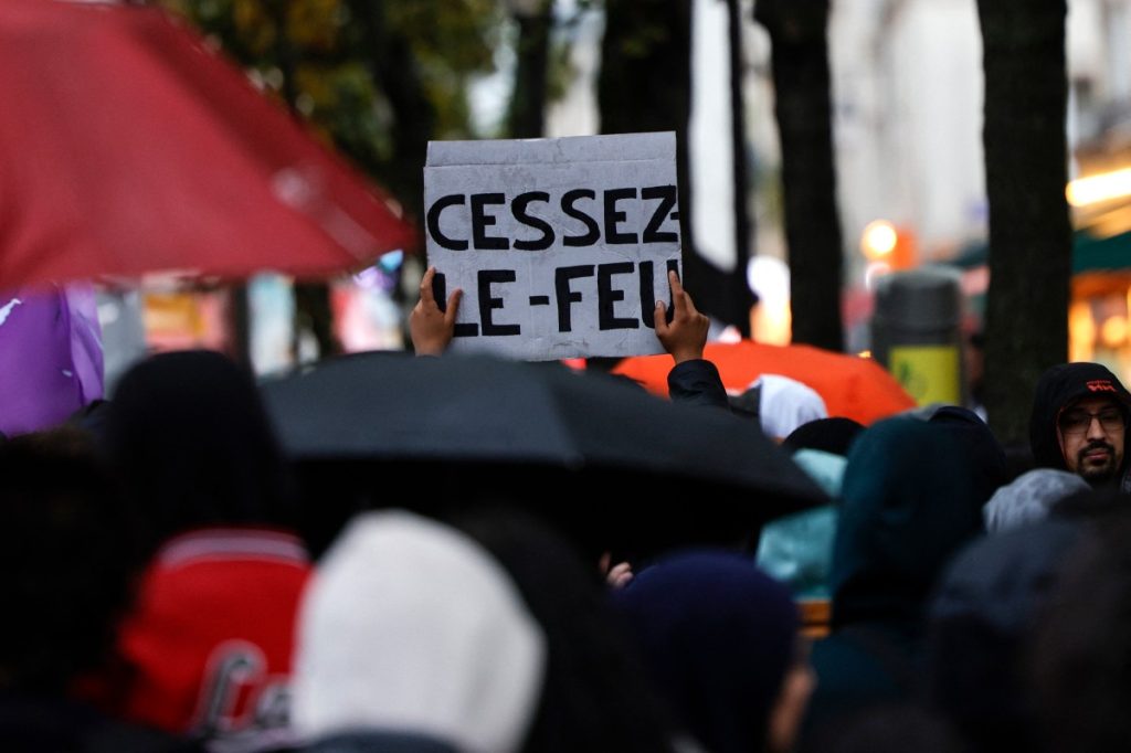 A protester holds a placard reading "Cease fire" during a demonstration in support to Palestinians in central Paris on October 28, 2023. - Paris administrative court validated on October 28, 2023, a prefectoral ban on a demonstation in support to the Palestinians, notably due to the "gravity of the risks of troubling public order". (Photo by Geoffroy Van der Hasselt / AFP)