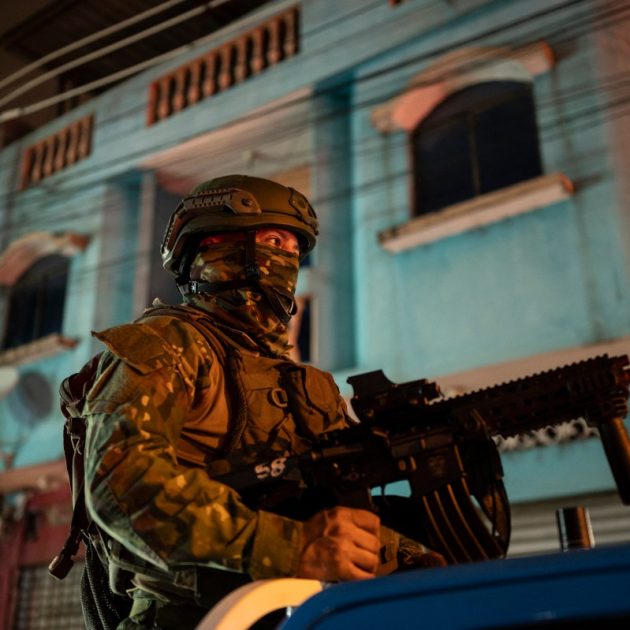 A soldier from the 5th Infantry Brigade keeps watch at the top of a pick-up truck during a security operation and search for suspects during the curfew, in a poor neighbourhood of Guayaquil, Ecuador, in the early hours of January 12, 2024. - Ecuador's armed forces were engaged in a brutal standoff with organized crime Thursday, deploying more than 22,400 soldiers to put down a campaign of terror waged by gangs that has claimed 16 lives.With an armed presence on the streets, patrols by land, sea and air, random body and car searches, prison raids and the enforcement of a curfew, the government of President Daniel Noboa has vowed not to yield in its "war" with 22 criminal gangs. (Photo by Yuri CORTEZ / AFP)