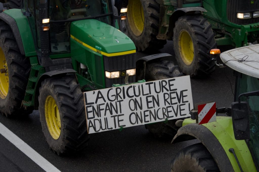 A placard reading "Agriculture : one dreams of it as a child but dies from it as an adult" hands on a tractor as French farmers block the A71 highway to protest over taxation and declining income, in Levet near Bourges, on January 24, 2024. - Europe's farmers are in revolt. The fury has led to road blockages and tractor parades in the past few weeks, with farmers taking their protests to the street in France, Germany, Poland and Romania, after the Netherlands earlier. From rising fuel costs to anger over green regulations to what farmers' say is unfair competition from Ukrainian imports, the list of grievances is long. (Photo by GUILLAUME SOUVANT / AFP)