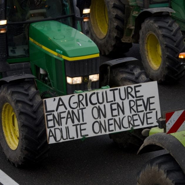 A placard reading "Agriculture : one dreams of it as a child but dies from it as an adult" hands on a tractor as French farmers block the A71 highway to protest over taxation and declining income, in Levet near Bourges, on January 24, 2024. - Europe's farmers are in revolt. The fury has led to road blockages and tractor parades in the past few weeks, with farmers taking their protests to the street in France, Germany, Poland and Romania, after the Netherlands earlier. From rising fuel costs to anger over green regulations to what farmers' say is unfair competition from Ukrainian imports, the list of grievances is long. (Photo by GUILLAUME SOUVANT / AFP)