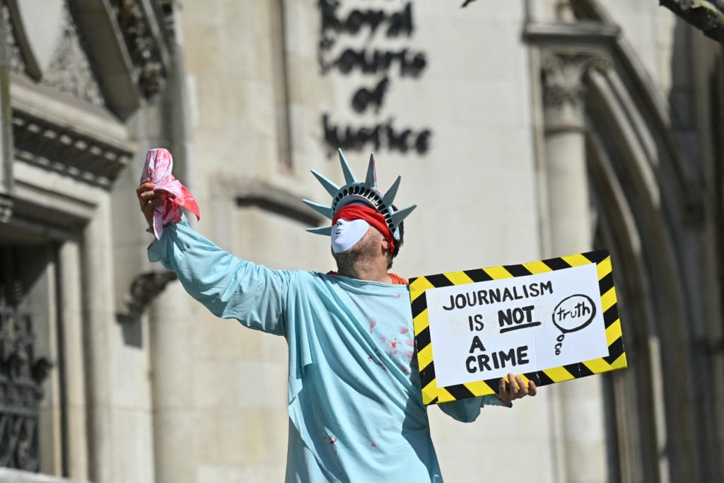 A supporter in a costume of the Statue of Liberty holds a placard in support of Wikileaks founder Julian Assange, outside the Royal Courts of Justice in the City of London on August 11, 2021, during a preliminary appeal hearing of the US case for the extradition of Assange to the US. Julian Assange's fiancée called Wednesday on President Joe Biden to drop the US case against the WikiLeaks founder after a British court granted the US permission to appeal for his extradition. (Photo by JUSTIN TALLIS / AFP)