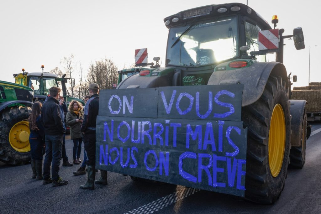 A tractor with a placard bearing the slogan "We feed you, but we are dying", during a farmers protest at the Daussoulx interchange between highways E40 and E411, near Namur, organised by the Federation of young Walloon farmers (FJA), on January 28, 2024. - Farmers protest across Europe are growing as they demand better conditions to grow produce and maintain a proper income. (Photo by Simon Wohlfahrt / AFP)