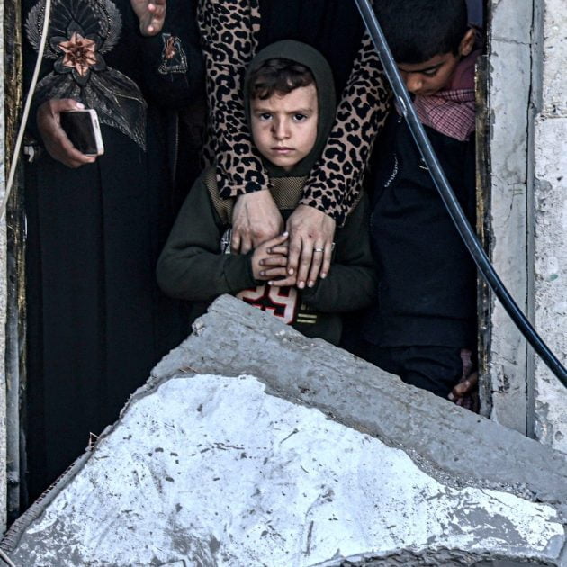 A child looks on while standing with others through the doorway of a room adjacent to a destroyed building, in the aftermath of Israeli bombardment on Rafah in the southern Gaza Strip on February 7, 2024, amid the ongoing conflict between Israel and the Palestinian militant group Hamas. (Photo by SAID KHATIB / AFP)