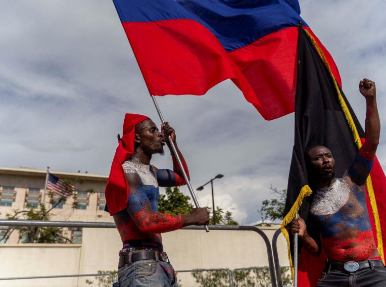 Demonstrators wave a Russian flag in front of the American Embassy during Jean-Jacques Dessalines Day in Port-au-Prince, Haiti, October 17, 2022. People are protesting the Prime Minister and Americans as the nation celebrates the 216th anniversary of the assassination of Dessalines, Haitian independence hero and founding father. (Photo by Richard Pierrin / AFP)