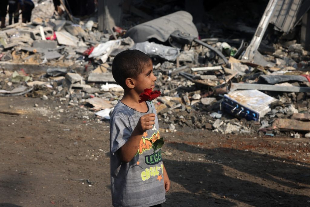 EDITORS NOTE: Graphic content / A young boy holds a fake flower found amid the rubble of a building in the aftermath of Israeli strikes in Gaza City on October 28, 2023. - Israeli air strikes destroyed hundreds of buildings in the Gaza Strip overnight, the civil defence service in the Hamas-controlled Palestinian territory said on October 28. (Photo by MOHAMMED ABED / AFP)