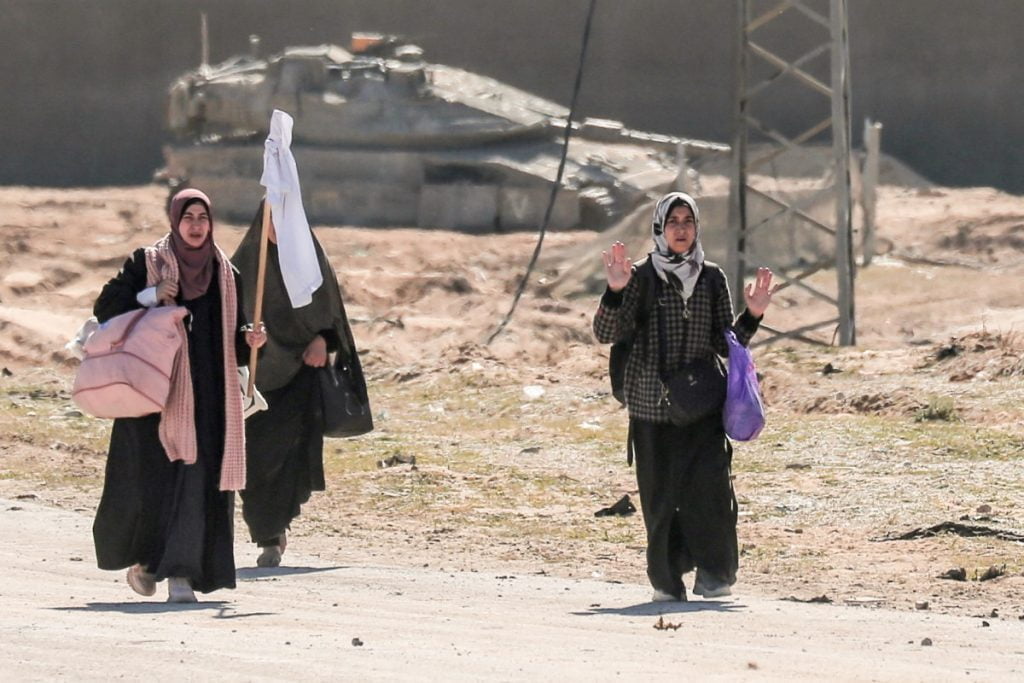 Displaced Palestinian women carrying their belongings lift a makeshift white flag as they walk past Israeli forces while fleeing the Hamad City area in Khan Yunis in the southern Gaza Strip on March 5, 2024, amid the ongoing conflict between Israel and the Hamas movement. (Photo by AFP)