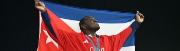 Gold medallist Cuba's Mijain Lopez Nunez poses with the Cuban flag and his medal after the presentation ceremony for the men's greco-roman 130kg wrestling event at the Champ-de-Mars Arena during the Paris 2024 Olympic Games, in Paris on August 6, 2024. (Photo by Punit PARANJPE / AFP)