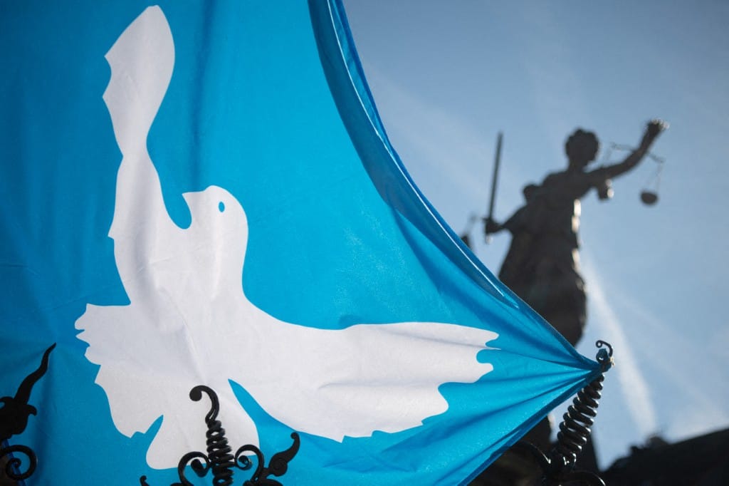 18 April 2022, Hessen, Frankfurt/Main: A flag with a dove of peace hangs before the beginning of the final rally of the Easter march of the "Netzwerk Friedenskooperative" at the Fountain of Justice with the statue of Justitia, the goddess of justice with executioner's sword and scales. Under the slogan "Lay down your arms! Stop the war in Ukraine. Stop the 100-billion-euro rearmament program", several hundred participants took part in the Easter march. Photo: Sebastian Gollnow/dpa (Photo by Sebastian Gollnow / DPA / dpa Picture-Alliance via AFP)