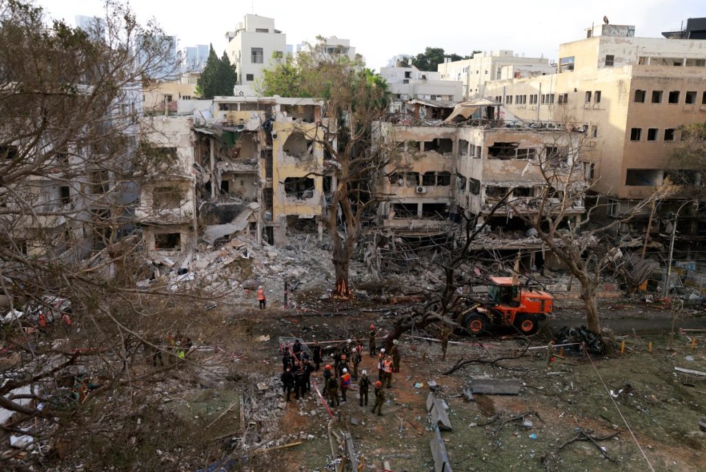 Rescuers stand amid the debris of damaged building in the Israeli city of Tel Aviv following an Iranian missile attack on June 16, 2025. Israel's Magen David Adom emergency service said on June 16 that three people were killed and 74 wounded following Iran's latest missile attack. It said two women and one man had been killed, without giving a precise location, but adding rescue operations were ongoing in two places. (Photo by Menahem KAHANA / AFP)