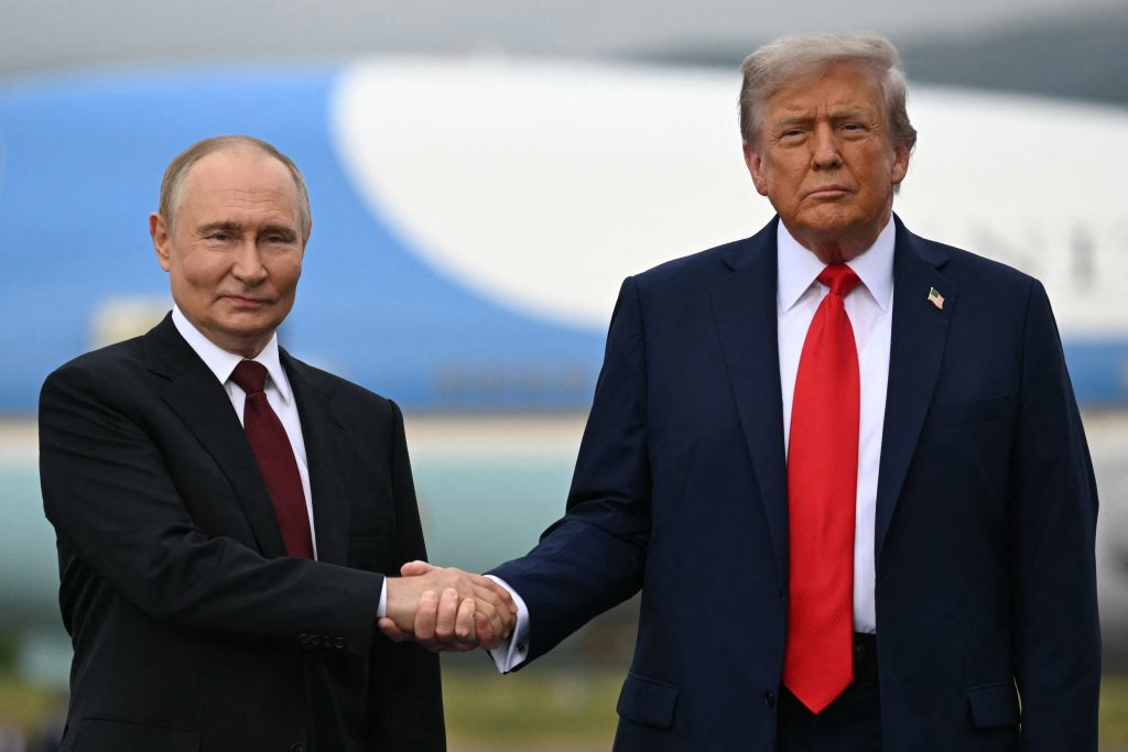 US President Donald Trump (R) and Russian President Vladimir Putin shake hands as they pose on a podium on the tarmac after arrival at Joint Base Elmendorf-Richardson in Anchorage, Alaska, on August 15, 2025. Putin is in Alaska at the invitation of Trump in his first visit to a Western country since he ordered the 2022 invasion of Ukraine that has killed tens of thousands of people. (Photo by ANDREW CABALLERO-REYNOLDS / AFP)