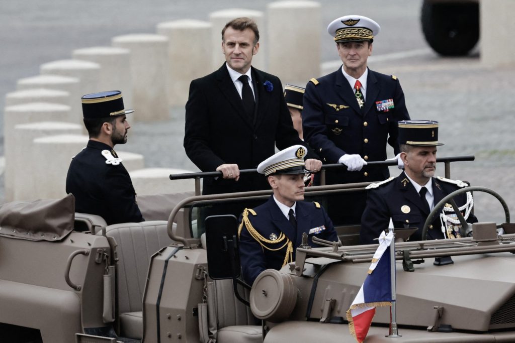 President of France Emmanuel Macron (L) and France's Chief of Military Staff of the President of the Republic (CEMP) Fabien Mandon ride aboard the command car as they arrive to attend a ceremony at the Arc de Triomphe in Paris, on November 11, 2025, as part of the commemorations marking the 107th anniversary of the November 11, 1918, Armistice, ending World War I (WWI). (Photo by STEPHANE DE SAKUTIN / AFP)