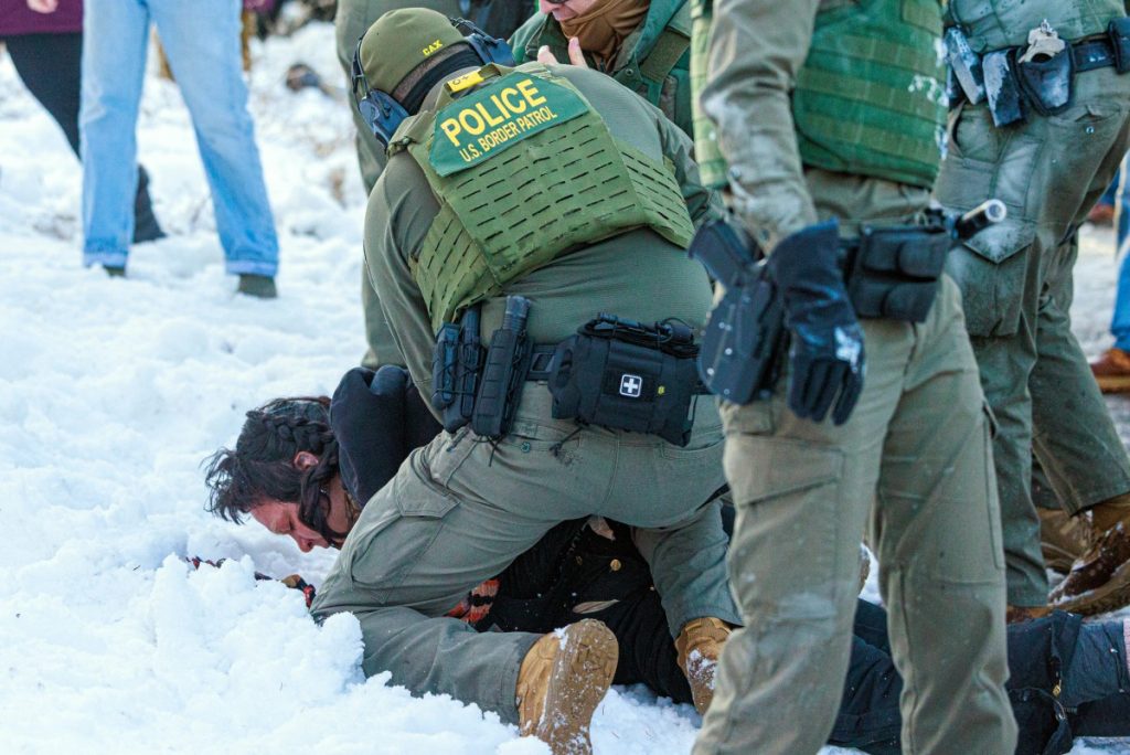 US Border Patrol agents detain a person near Roosevelt High School during dismissal time as federal immigration enforcement actions sparked protests in Minneapolis, Minnesota, on January 7, 2026. An immigration officer in Minneapolis shot dead a woman Wednesday, triggering outrage from local leaders even as US President Donald Trump claimed the officer acted in self-defense. Minneapolis Mayor Jacob Frey deemed the government's allegation that the woman was attacking federal agents "bullshit," and called on Immigration and Customs Enforcement (ICE) officers conducting a second day of mass raids to leave Minneapolis. (Photo by Kerem YUCEL / AFP)
