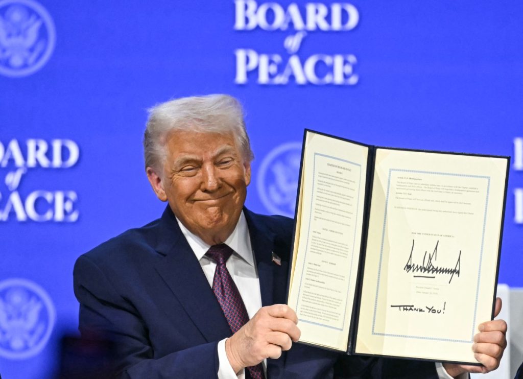 US President Donald Trump holds a signed founding charter at the "Board of Peace" meeting during the World Economic Forum (WEF) annual meeting in Davos on January 22, 2026. US President Donald Trump will show off his new "Board of Peace" at Davos on January 22, 2026 burnishing his claim to be a peacemaker a day after backing off his own threats against Greenland. Originally meant to oversee the rebuilding of Gaza after the war between Hamas and Israel, the board's charter does not limit its role to the Strip, and has sparked concerns that Trump wants it to rival the United Nations. (Photo by Fabrice COFFRINI / AFP)