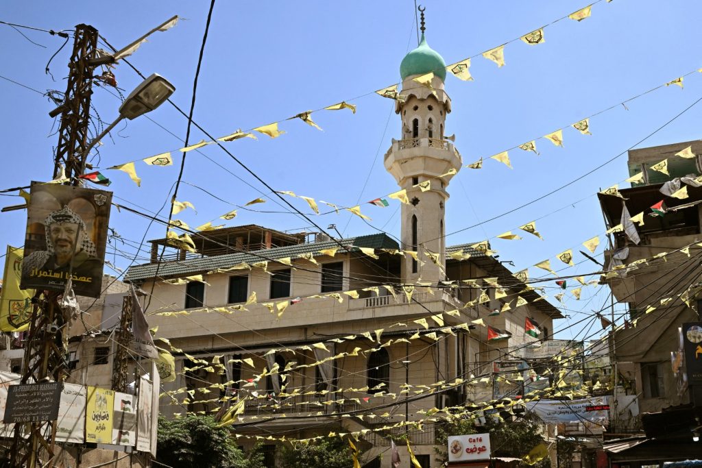 Flags of Palestine, of the Palestinian Fateh movement, and posters of its late leader and Palestinian president Yasser Arafat hang across an entrance to the Burj al Barajneh camp for Palestinian refugees in Beirut's southern suburbs on May 20, 2025. Palestinian President Mahmud Abbas is due in Lebanon on May 21. (Photo by Joseph EID / AFP)