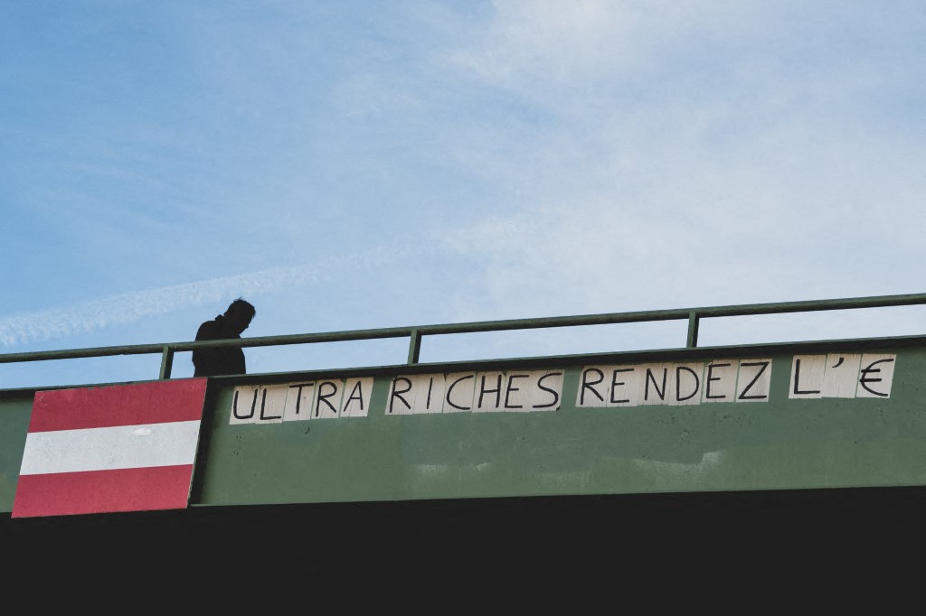 Illustration of a collage on the Moselle footbridge with the words Ultra-rich, give back the money Paris, France, November 1, 2025. Illustration d un collage sur la passerelle de la Moselle ou il est inscrit Ultra riches rendez l argent a Paris, France le 01 Novembre 2025. (Photo by Carine Schmitt / Hans Lucas via AFP)