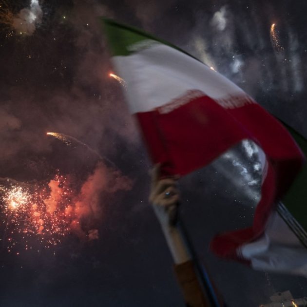 A young Iranian woman waves a national flag while fireworks illuminate the sky during a state-run religious festival to mark Imam Mahdi's birthday anniversary in downtown Tehran, Iran, on February 4, 2026. This occurs about one month after deadly anti-government protests in Iran. (Photo by Morteza Nikoubazl/NurPhoto) (Photo by Morteza Nikoubazl / NurPhoto via AFP)