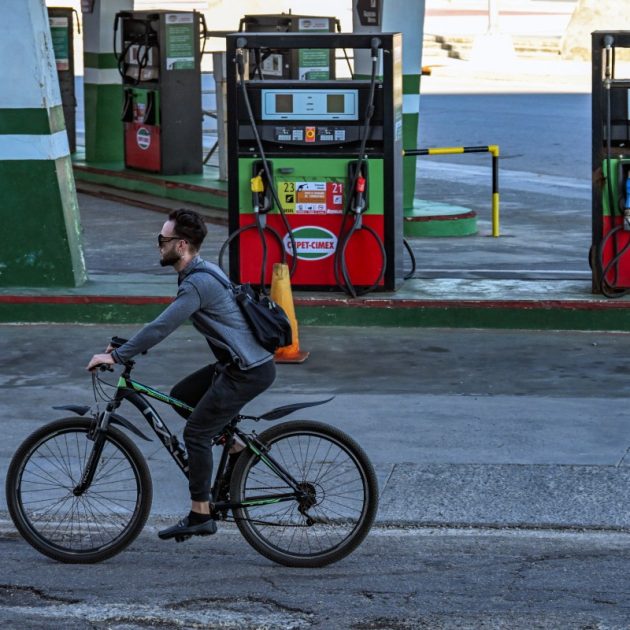 A man rides his bicycle past an empty gas station in Havana on February 19, 2026. Faced with a severe energy crisis exacerbated by US sanctions, private companies in Cuba are attempting to import fuel after the island's government agreed to end its monopoly on the sector. (Photo by YAMIL LAGE / AFP)