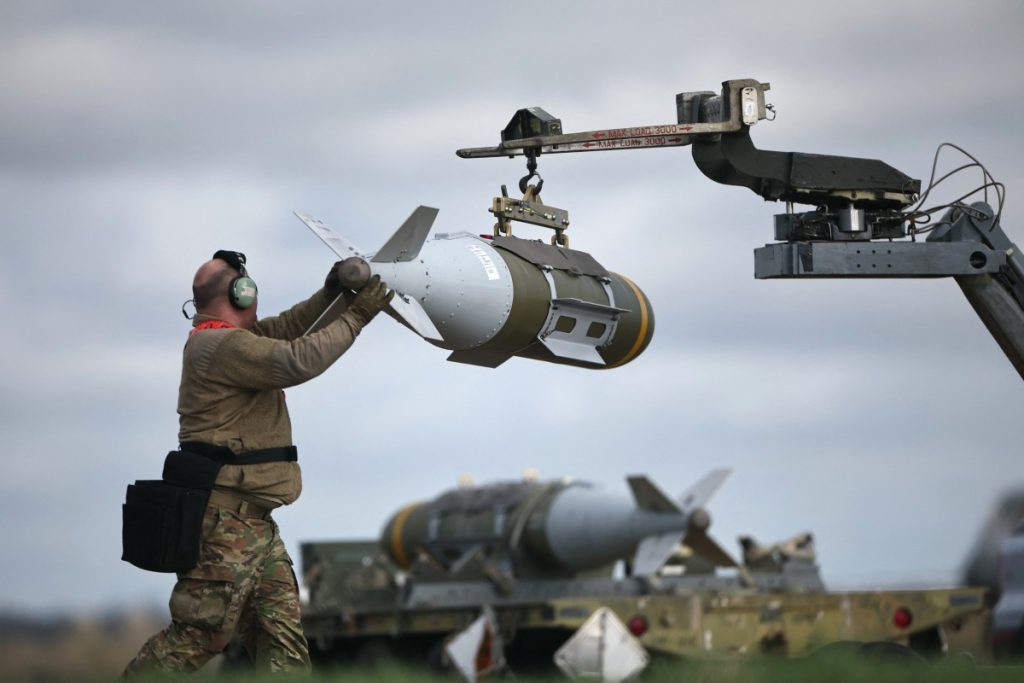 US Military personnel take away Joint Direct Attack Munitions (JDAMs), removed from a US Air Force B-1 Lancer bomber at RAF Fairford in south-west England on March 15, 2026. Fairford is one of two bases, along with the Diego Garcia facility in the Indian Ocean, that the UK has given the US permission to use for "specific defensive operations into Iran" to destroy Iranian missiles at source, the British defence minister said in a statement. (Photo by Henry NICHOLLS / AFP)