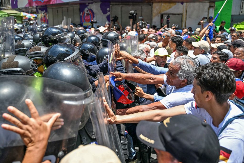 Opponents to the government of Venezuelan interim President Delcy Rodriguez confront the police as they demonstrate in demand of salary and pension raises in Caracas on April 9, 2026. (Photo by Juan BARRETO / AFP)