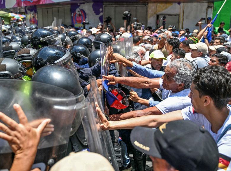 Opponents to the government of Venezuelan interim President Delcy Rodriguez confront the police as they demonstrate in demand of salary and pension raises in Caracas on April 9, 2026. (Photo by Juan BARRETO / AFP)