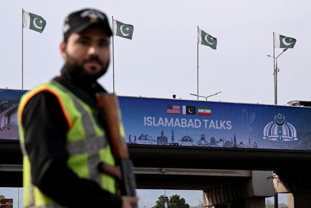 A policeman stands guard in front of a digital screen displaying news of USIran peace talks along a road in Islamabad on April 10, 2026. A cloud of uncertainty hung April 10 over the scheduled start of talks in Pakistan between the United States and Iran, with no announcement yet on the arrival of negotiators and both sides accusing the other of failing to properly implement a fragile ceasefire. (Photo by Farooq NAEEM / AFP)