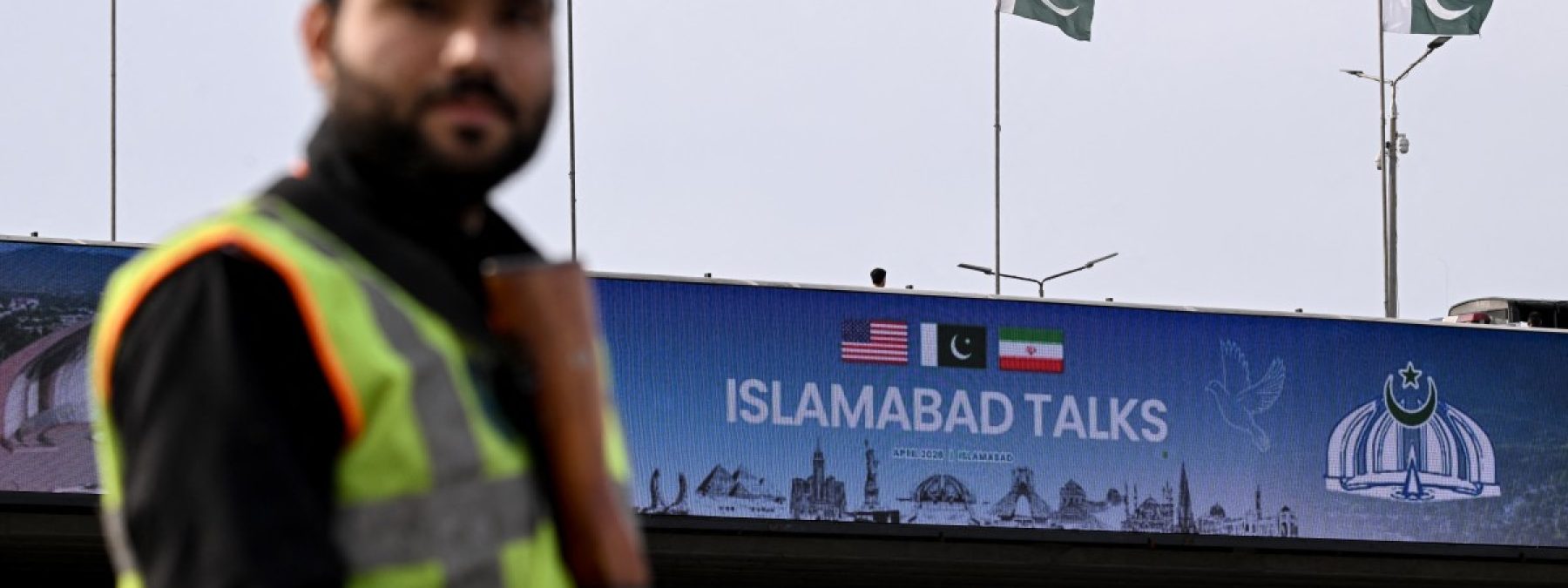 A policeman stands guard in front of a digital screen displaying news of USIran peace talks along a road in Islamabad on April 10, 2026. A cloud of uncertainty hung April 10 over the scheduled start of talks in Pakistan between the United States and Iran, with no announcement yet on the arrival of negotiators and both sides accusing the other of failing to properly implement a fragile ceasefire. (Photo by Farooq NAEEM / AFP)