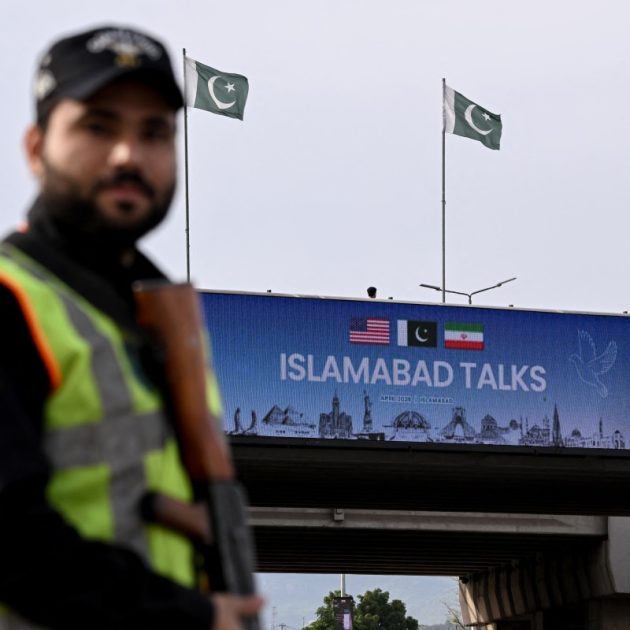 A policeman stands guard in front of a digital screen displaying news of USIran peace talks along a road in Islamabad on April 10, 2026. A cloud of uncertainty hung April 10 over the scheduled start of talks in Pakistan between the United States and Iran, with no announcement yet on the arrival of negotiators and both sides accusing the other of failing to properly implement a fragile ceasefire. (Photo by Farooq NAEEM / AFP)