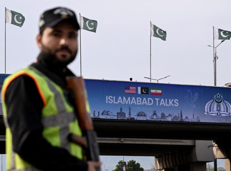A policeman stands guard in front of a digital screen displaying news of USIran peace talks along a road in Islamabad on April 10, 2026. A cloud of uncertainty hung April 10 over the scheduled start of talks in Pakistan between the United States and Iran, with no announcement yet on the arrival of negotiators and both sides accusing the other of failing to properly implement a fragile ceasefire. (Photo by Farooq NAEEM / AFP)