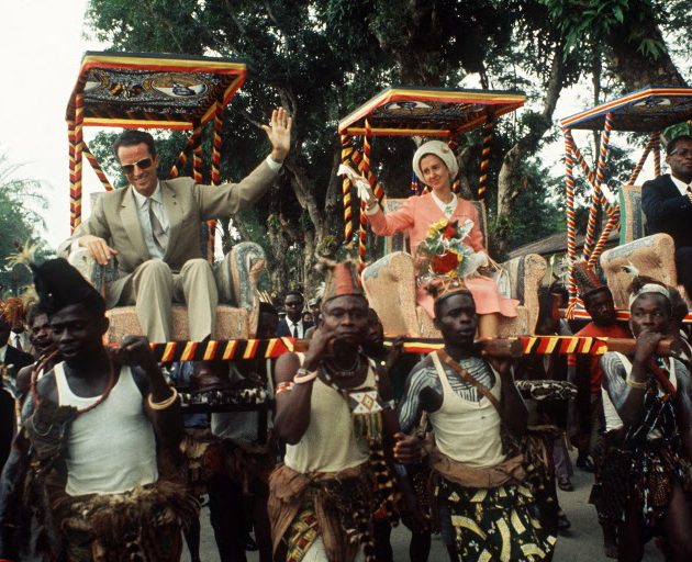 King Baudouin of Belgium and his wife Queen Fabiola wave to wellwishers as they are carried 26 June 1970 in the armchairs during their trip to Kinshasa, in Congo. (Photo by AFP)