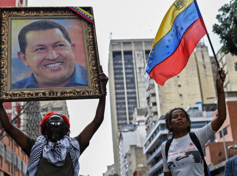 Supporters of Venezuelan President Nicolas Maduro hold a portrait of late Venezuelan President Hugo Chavez and a Venezuelan national flag during a march in solidarity with the social movements that have exploded in Latin American countries in the last days, in Caracas, on October 24, 2019. Thousands of government supporters paraded down a main avenue to show their support for the protests in Chile, Honduras, Ecuador, and to support Bolivian President Evo Morales. (Photo by Yuri CORTEZ / AFP)