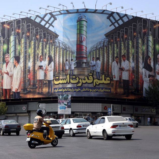 Iranians drive next to a billboard displaying pictures of nuclear scientists, centrifuges and a sentence reading in Farsi: " Science is the power", at the Enqelab square in Tehran, on August 29, 2025. Iran said on August 29 the decision by European powers to trigger a mechanism reimposing sanctions under a moribund 2015 nuclear deal would undermine Tehran's cooperation with the United Nations nuclear watchdog. Britain, France and Germany -- known as the E3 -- triggered the so-called "snapback" mechanism after weeks of warnings, citing Iran's continued non-compliance with its commitments under the 2015 nuclear agreement (Photo by AFP)