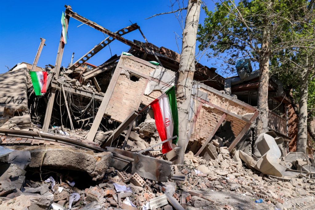 Iranian national flags are placed by the rubble of a collapsed building following strikes at Sharif University of Technology in Tehran on April 7, 2026. Gas supply was restored on April 6 after being cut in parts of Tehran following an attack in the early hours on a gas pressure reduction station and metering facilities at Sharif University of Technology, causing a leak. (Photo by ATTA KENARE / AFP) /