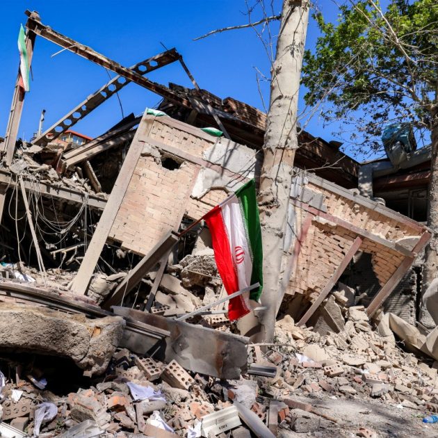 Iranian national flags are placed by the rubble of a collapsed building following strikes at Sharif University of Technology in Tehran on April 7, 2026. Gas supply was restored on April 6 after being cut in parts of Tehran following an attack in the early hours on a gas pressure reduction station and metering facilities at Sharif University of Technology, causing a leak. (Photo by ATTA KENARE / AFP) /
