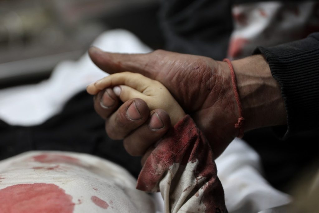 EDITORS NOTE: Graphic content / A relative holds the hand of three-year-old Yahya al-Malahi, who was killed in an Israeli strike ahead of her funeral in Gaza City on April 14, 2026. Gaza's civil defence agency said on April 14 four people, one of them a toddler, were killed in an Israeli strike in the northern part of the Palestinian territory. Violence continues to grip the war-torn Gaza Strip despite a ceasefire which came into effect on October 10, with both Israel and Hamas regularly accusing each other of violations. (Photo by Omar AL-QATTAA / AFP)