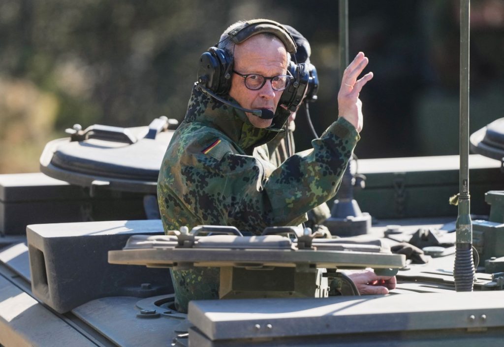 German Chancellor Friedrich Merz waves as he is driven in a GTK Boxer tank at the German army barracks in Munster, northern Germany, on April 30, 2026, as they visit the troops of the German Army. (Photo by Markus Schreiber / POOL / AFP)