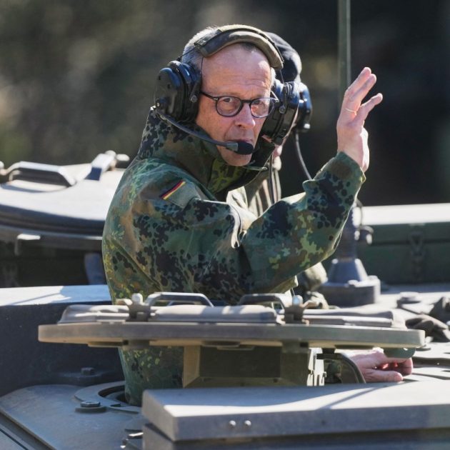 German Chancellor Friedrich Merz waves as he is driven in a GTK Boxer tank at the German army barracks in Munster, northern Germany, on April 30, 2026, as they visit the troops of the German Army. (Photo by Markus Schreiber / POOL / AFP)