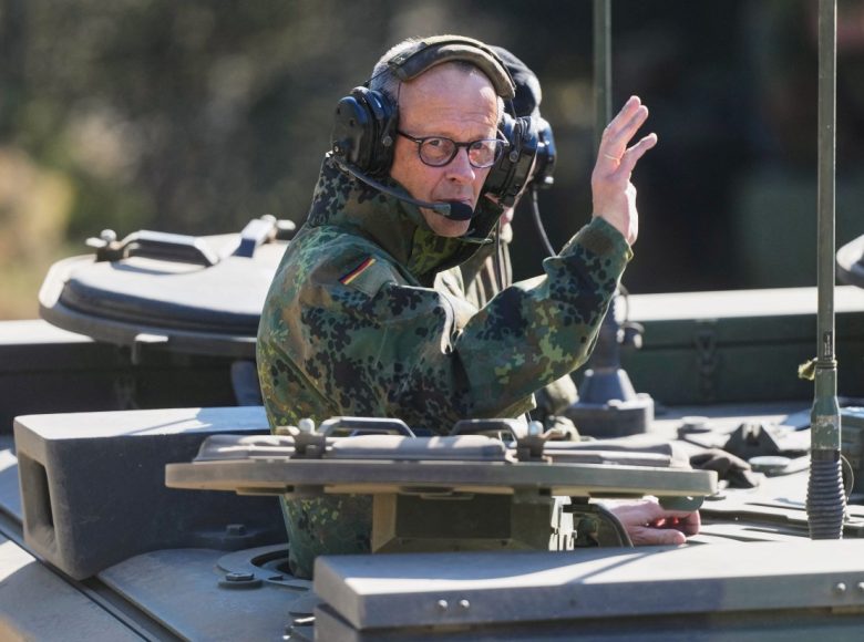 German Chancellor Friedrich Merz waves as he is driven in a GTK Boxer tank at the German army barracks in Munster, northern Germany, on April 30, 2026, as they visit the troops of the German Army. (Photo by Markus Schreiber / POOL / AFP)