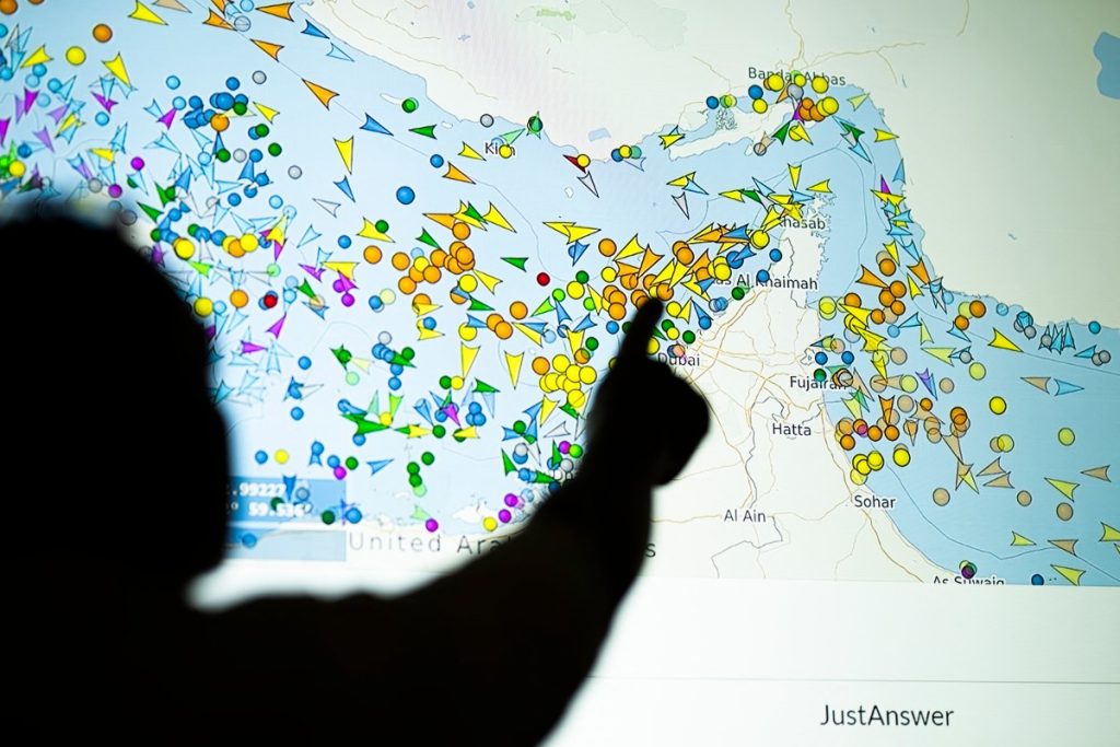A photo illustration taken in Nicosia on May 4, 2026, shows a person in front of a large screen displaying vessel movements in the Strait of Hormuz on a ship-tracking website. Iran's navy fired 'warning shots' at US warships in the Strait of Hormuz on May 4, state media said, after the American military sent cruisers into the Gulf as part of a plan to help trapped commercial vessels leave. Earlier, US President Donald Trump had announced a plan to guide ships from neutral countries out of the Gulf, saying it was a humanitarian effort to help their stranded crews. (Photo by AFP)
