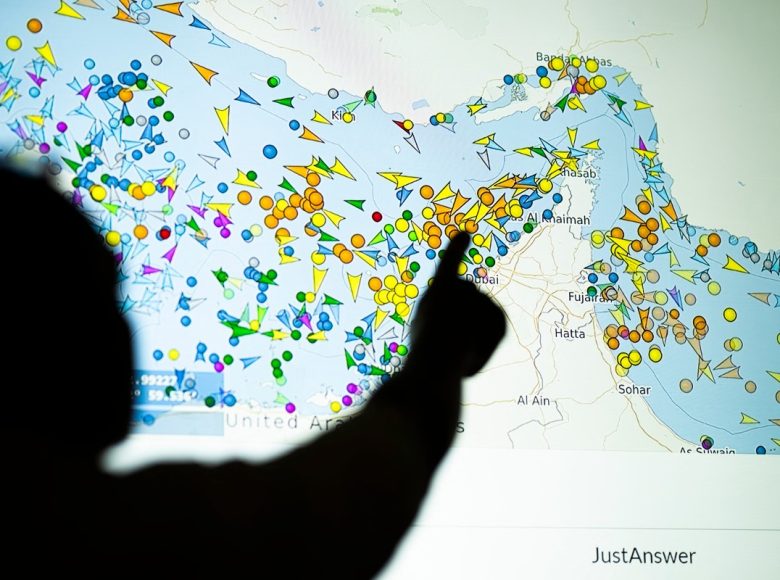 A photo illustration taken in Nicosia on May 4, 2026, shows a person in front of a large screen displaying vessel movements in the Strait of Hormuz on a ship-tracking website. Iran's navy fired 'warning shots' at US warships in the Strait of Hormuz on May 4, state media said, after the American military sent cruisers into the Gulf as part of a plan to help trapped commercial vessels leave. Earlier, US President Donald Trump had announced a plan to guide ships from neutral countries out of the Gulf, saying it was a humanitarian effort to help their stranded crews. (Photo by AFP)