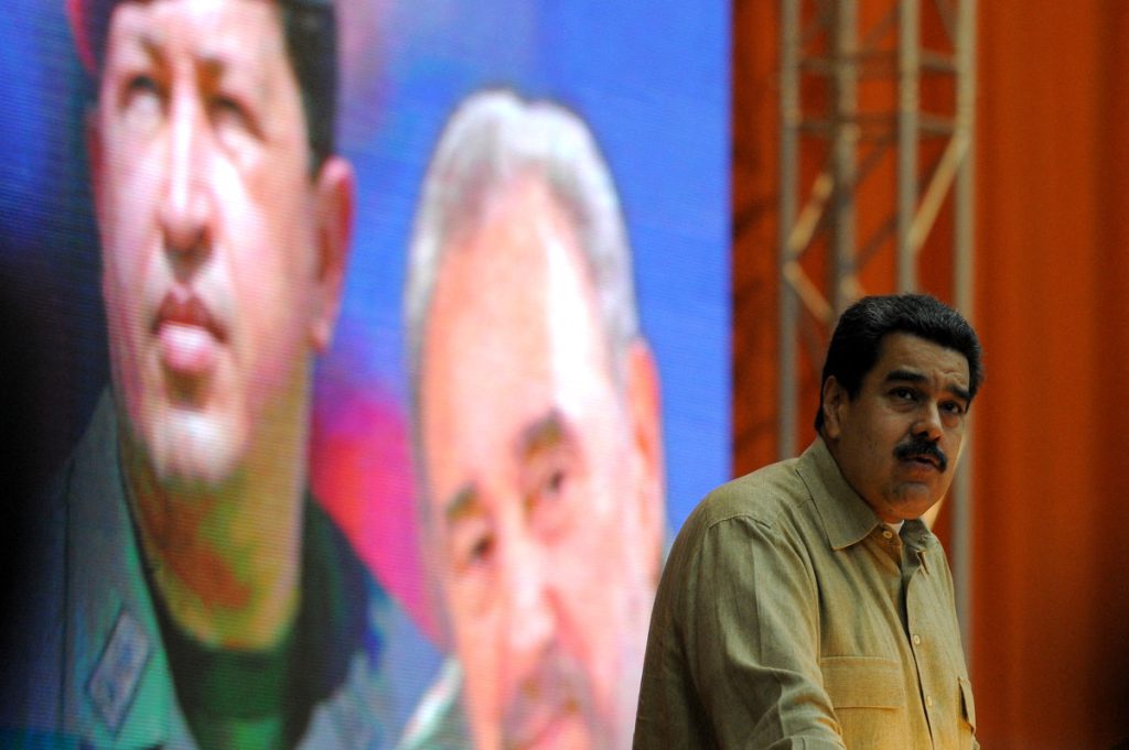 Venezuelan President Nicolas Maduro delivers a speech at the XII Anniversary of the Bolivarian Alliance for the Peoples of Our America (ALBA) at the Convention Palace in Havana, on December 14, 2016, in front of a poster of the late Venezuelan and Cuban leaders Hugo Chavez and Fidel Castro. (Photo by YAMIL LAGE / AFP)