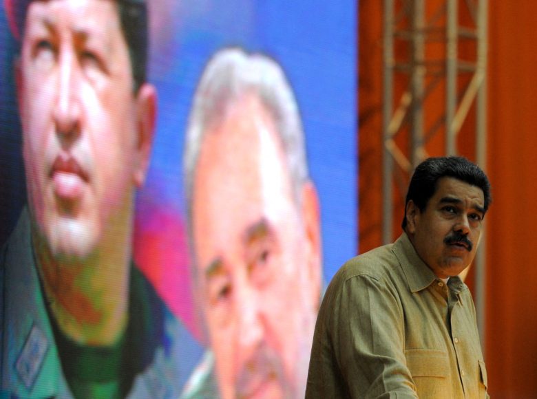 Venezuelan President Nicolas Maduro delivers a speech at the XII Anniversary of the Bolivarian Alliance for the Peoples of Our America (ALBA) at the Convention Palace in Havana, on December 14, 2016, in front of a poster of the late Venezuelan and Cuban leaders Hugo Chavez and Fidel Castro. (Photo by YAMIL LAGE / AFP)