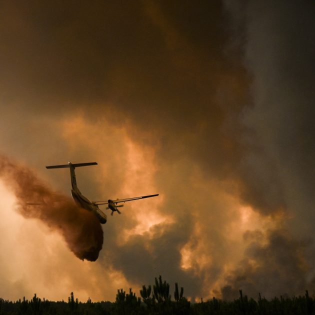 A Dash 8 firefighting aircraft sprays fire retardant over trees during a wildfire near Belin-Beliet in Gironde, southwestern France, on August 10, 2022. (Photo by Philippe LOPEZ / AFP)