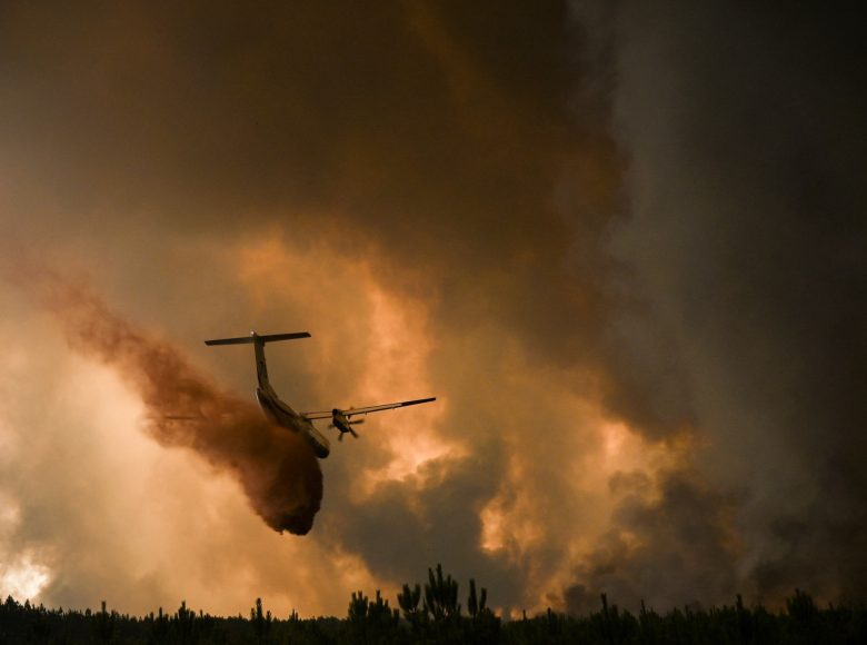 A Dash 8 firefighting aircraft sprays fire retardant over trees during a wildfire near Belin-Beliet in Gironde, southwestern France, on August 10, 2022. (Photo by Philippe LOPEZ / AFP)