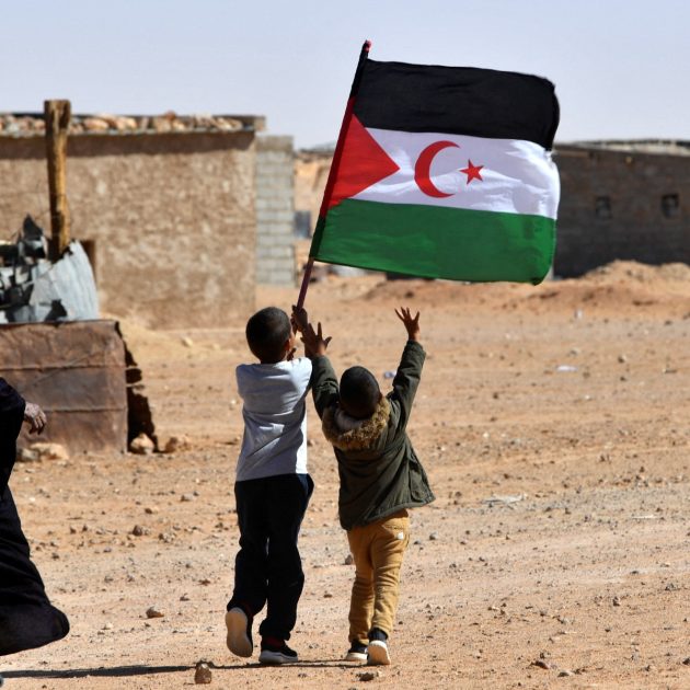 A child raises the flag of the Sahrawi Arab Democratic Republic (SARD) during celebrations marking the 47th anniversary of the declaration of national unity of the Sahrawi people, in the Aousserd refugee camp on the outskirts of the southwestern Algerian city of Tindouf, on October 12, 2022. (Photo by Ryad KRAMDI / AFP)