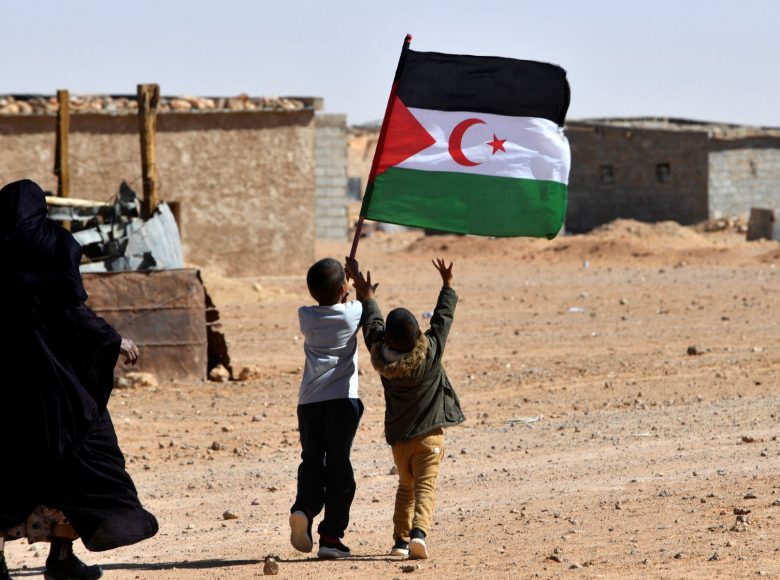 A child raises the flag of the Sahrawi Arab Democratic Republic (SARD) during celebrations marking the 47th anniversary of the declaration of national unity of the Sahrawi people, in the Aousserd refugee camp on the outskirts of the southwestern Algerian city of Tindouf, on October 12, 2022. (Photo by Ryad KRAMDI / AFP)