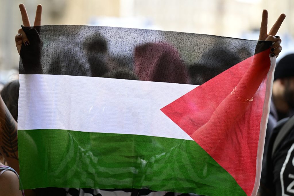 A demonstrator holds up a Palestinian flag outside the Humboldt University during a Pro-Palestinian protest in Berlin, on May 23, 2024. (Photo by JOHN MACDOUGALL / AFP)