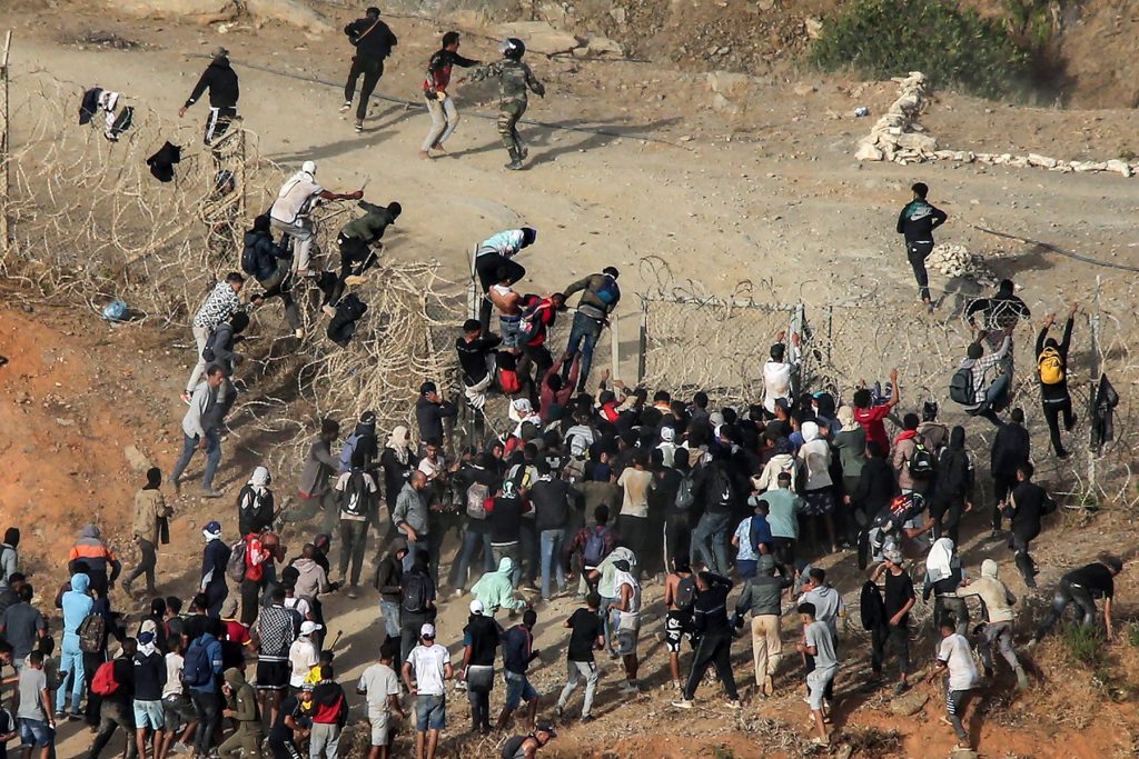 Migrants storm a barbed-wire fence as they attempt to cross the land border with Spain's African enclave of Ceuta near Fnideq in northern Morocco on September 15, 2024. (Photo by AFP)