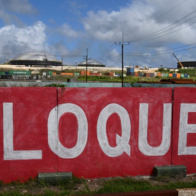 This view shows a mural reading blockade, with several fuel storage tanks in the background in the industrial zone of Matanzas, Cuba, on March 31, 2026. (Photo by YAMIL LAGE / AFP)